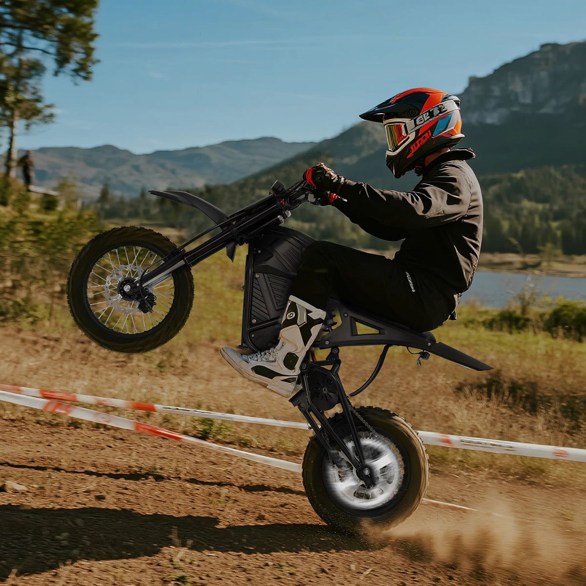 Person riding a VIPCOO H3 electric dirt bike on a track with mountains and trees in the background
